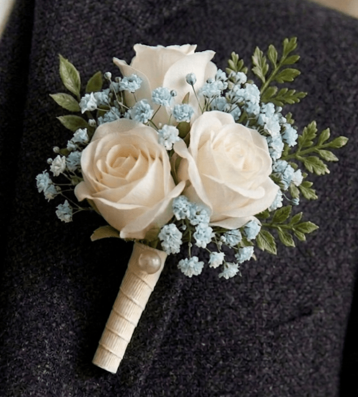 Boutonnière blanche et bleue pour mariage et bal, composée de 3 mini-roses blanches et de gypsophile, création artisanale de La Baraque à fleurs.
